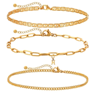 Gros plan d'un ensemble de trois bijoux dorés avec chaîne trombone et pendentif lettre H