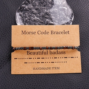 Detail of Morse Code bracelet with dark wood beads on kraft paper card packaging