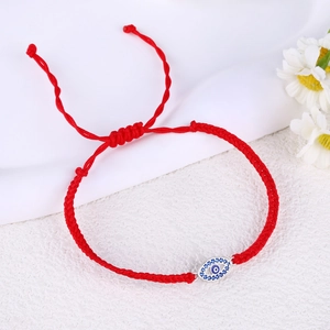 Macro detail of red woven Evil Eye bracelet with blue and white zircon stones