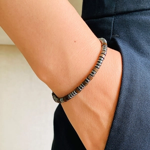 Close-up of Morse code bracelet with obsidian beads and hematite discs on a wrist