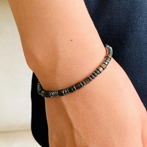 Close-up of unisex woven bracelet with dark obsidian beads and silver metal spacers