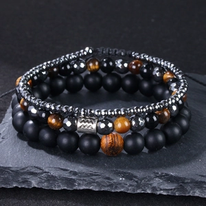 Makroaufnahme von Tigerauge- und Hämatit-Armbändern mit Wassermann-Zodiac-Anhänger auf Schiefer