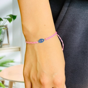Close-up of pink hand-woven evil eye bracelet with blue zircon charms on female wrist