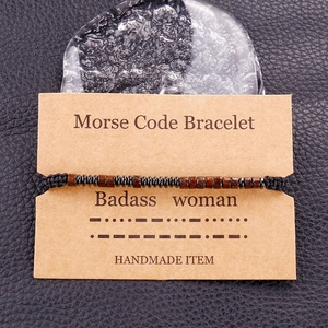 Detail of Morse code beaded bracelet on cardboard for badass woman with black leather background