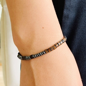 Macro detail of Morse code bracelet featuring hematite disks and dark wood beads