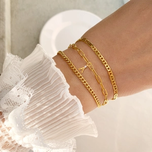 Vue détaillée de trois bracelets chaînes dorés incluant un pendentif lettre A