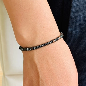 Close-up of Morse code bracelet with hematite and wooden beads on a wrist