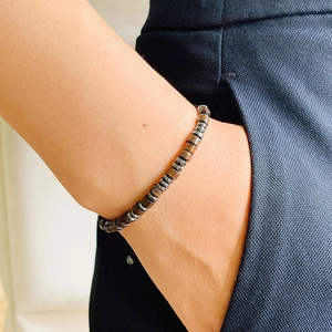 Detailed view of Morse code beaded bracelet with wooden beads on a male model wrist