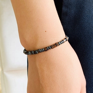 Close-up of beaded Morse code bracelet with dark wooden and metal beads on wrist