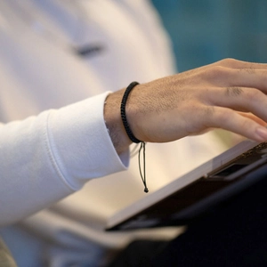Close-up of a black handmade braided cord bracelet on a wrist with adjustable drawstring