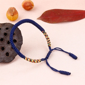 Detail of blue braided knot bracelet with colorful fiber accents on natural background