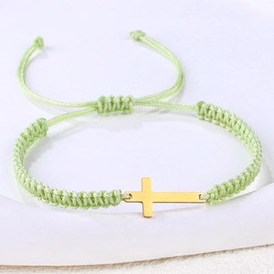 Close-up of hand-woven mint green cord bracelet with a polished gold cross pendant detail