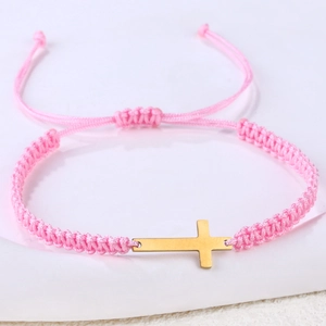 Detailed close-up of pink woven rope bracelet with gold cross and adjustable knot