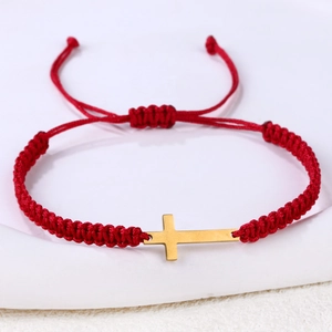 Detail of red handmade braided rope bracelet with a golden horizontal stainless steel cross