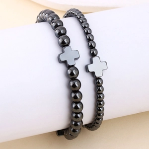 Dettaglio di braccialetti in perline di ematite con ciondolo a croce e fascia elastica