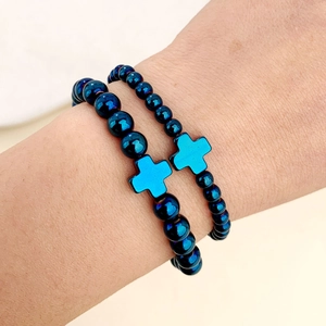 Dettaglio di braccialetti elastici in perline blu metallizzato con croci abbinate