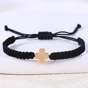 Nahaufnahme eines handgewebten schwarzen Armbands mit poliertem goldenem Edelstahlkreuz