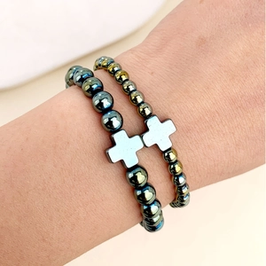 Dettaglio dei braccialetti elastici in ematite con ciondoli a croce indossati al polso