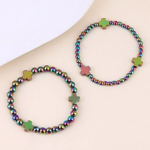 Dettaglio di due braccialetti di perline in ematite iridescente con croci pendenti