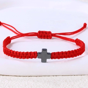 Detail eines roten handgeflochtenen Seilarmbands mit mattgrauem Edelstahl Kreuzanhänger