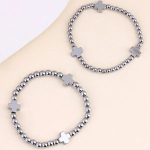 Dettaglio di bracciali con perle di ematite grigio scuro e ciondoli a croce stile neutro