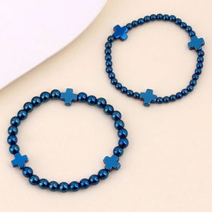Dettaglio macro di perline di ematite blu metallizzato e ciondoli a croce su bracciali elastici