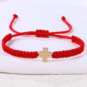 Detail eines roten gewebten Armbandes mit goldenem Edelstahlkreuz und Schiebeverschluss