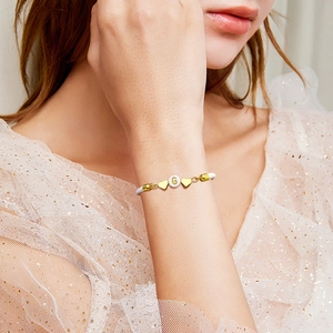 Minimalist white braided couple bracelet with gold letter G and heart charms on model