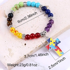 Macro shot of colorful stone beaded bracelet with puzzle cross charm on stone base