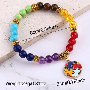 Detail of colorful stone beads bracelet with gold spacers and puzzle piece charm