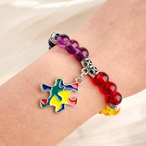 Detail view of colorful beaded autism awareness bracelet with puzzle piece charm on wrist