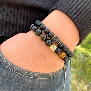 Close-up of black obsidian and tiger eye beaded bracelets set on a male wrist