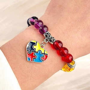 Close-up of autism awareness beaded bracelet featuring a colorful heart puzzle charm