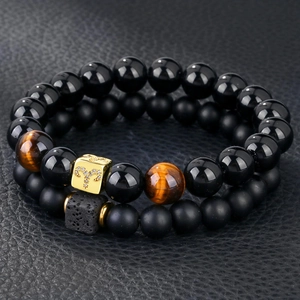 Macro detail of Aries zodiac gold charm on double layer black onyx and tiger eye beads