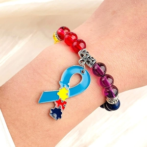 Close-up of autism awareness puzzle ribbon charm on a colorful natural stone bead bracelet