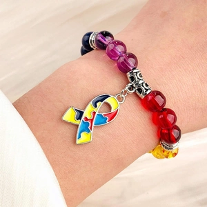 Detailed close-up of a colorful beaded bracelet with a symbolic puzzle ribbon charm