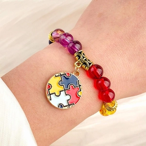 Macro detail of natural stone bead bracelet with a colorful enamel puzzle charm and gold spacers