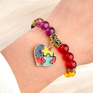 Detail of colorful beaded puzzle heart bracelet on wrist for autism awareness