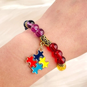 Close-up of beaded autism awareness bracelet with colorful stones and puzzle charm