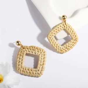 Detailed macro view of bohemian geometric square woven rattan earrings with gold studs