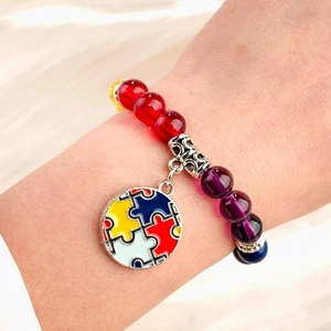 Colorful natural stone beaded bracelet with a puzzle enamel charm on a female wrist