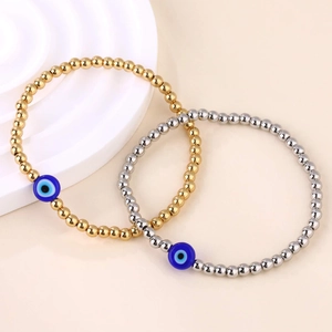 Detail van vergulde en verzilverde kralenarmbanden met blauwe evil eye bedels op een plateau