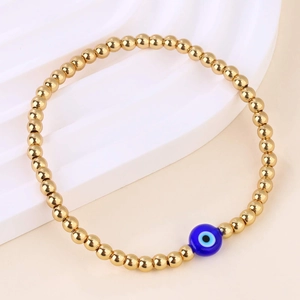 Detail van gouden kralenarmband met blauw glazen boze oog kraal en gepolijste glans