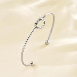 Bracciale rigido nodo in acciaio inossidabile argento con palline su sfondo in seta