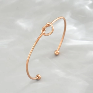 Dettaglio del bracciale rigido aperto in acciaio inossidabile oro rosa con nodo