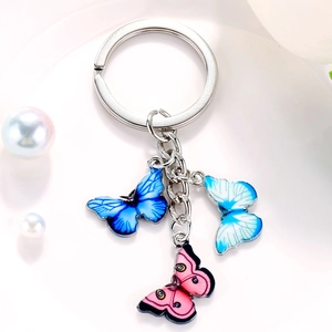 Detail shot of colorful butterfly keychain with blue and pink pendants on white surface