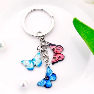 Macro detail of three-color butterfly keychain with pink and blue enamel pendants