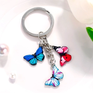 Close-up of butterfly metal keychain with colorful enamel pendants on a white plate