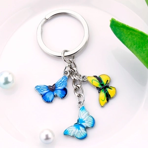 Close-up of a silver keychain featuring three colorful enamel butterfly pendants