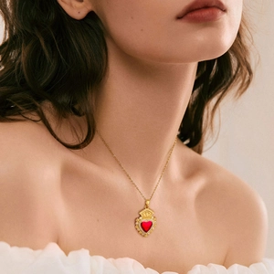 Dettaglio della collana con ciondolo a cuore rosso placcato oro indossata da una modella
